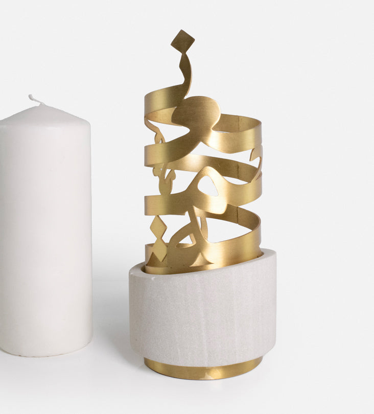 Sandstone candleholder featuring brass Arabic calligraphy cutout and sandstone base.