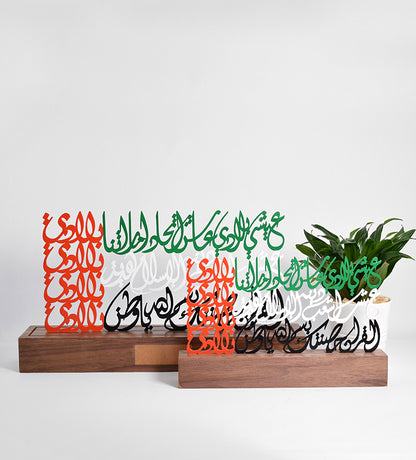 Metal sculpture of the united arab emirates flag featuring the UAE national anthem in Arabic calligraphy